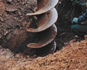 Construction-worker-operating-a-large-earth-auger-drill-in-soil_