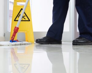 low-angle-closeup-person-cleaning-floor-with-mop-near-yellow-caution-wet-floor-sign-1024×683-1